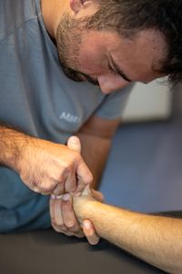 Ein Physiotherapeut des Institut in Mönchengladbach bei der Behandlungsmethode an der Hand die sich nicht nur auf Knochen und Muskeln konzentriert